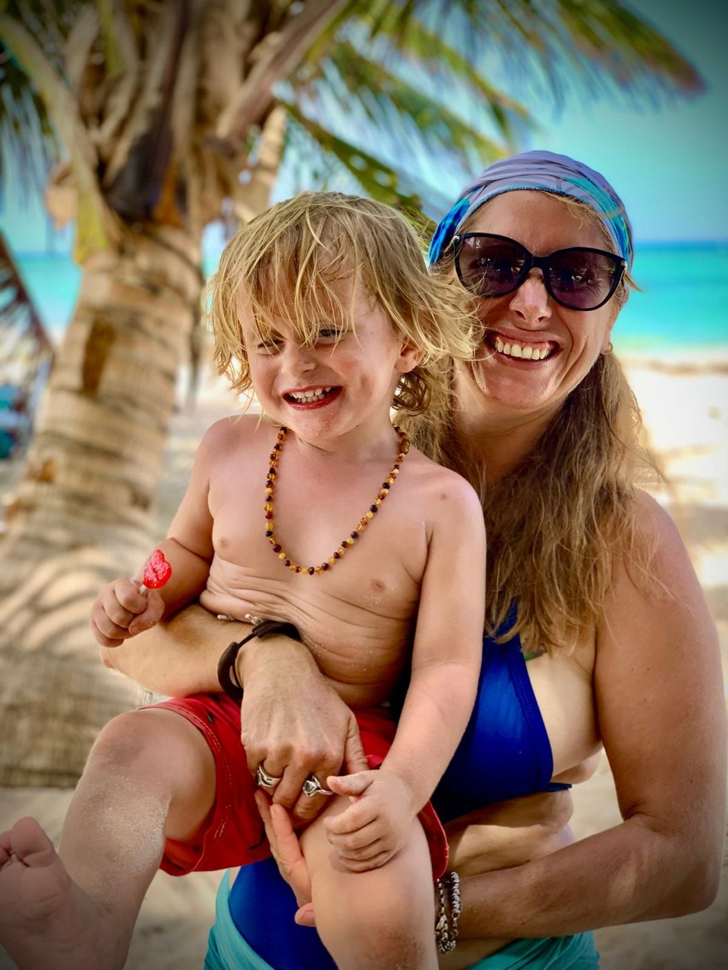 Maddy and Ricci on the beach under a palm